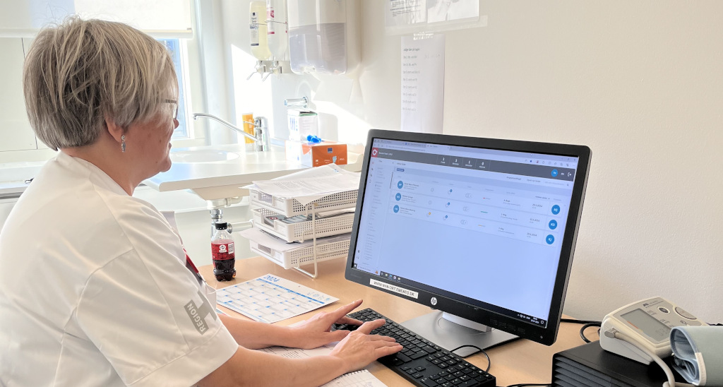 Sygeplejerske sidder ved skrivebord og skriver på computer