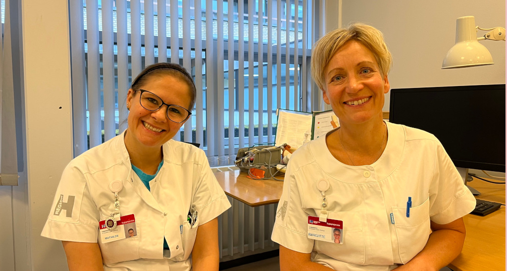 To sygeplejersker sidder i ambulatorie og smiler