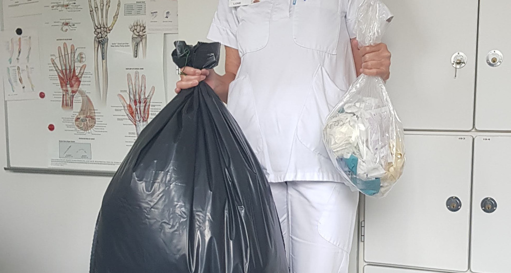 Sygeplejerske holder en stor pose og en lille pose i hænderne