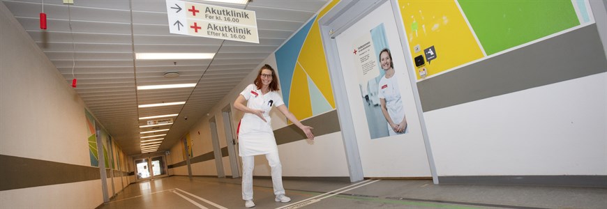 Foto af en sygeplejerske, der viser den nye skiltning frem